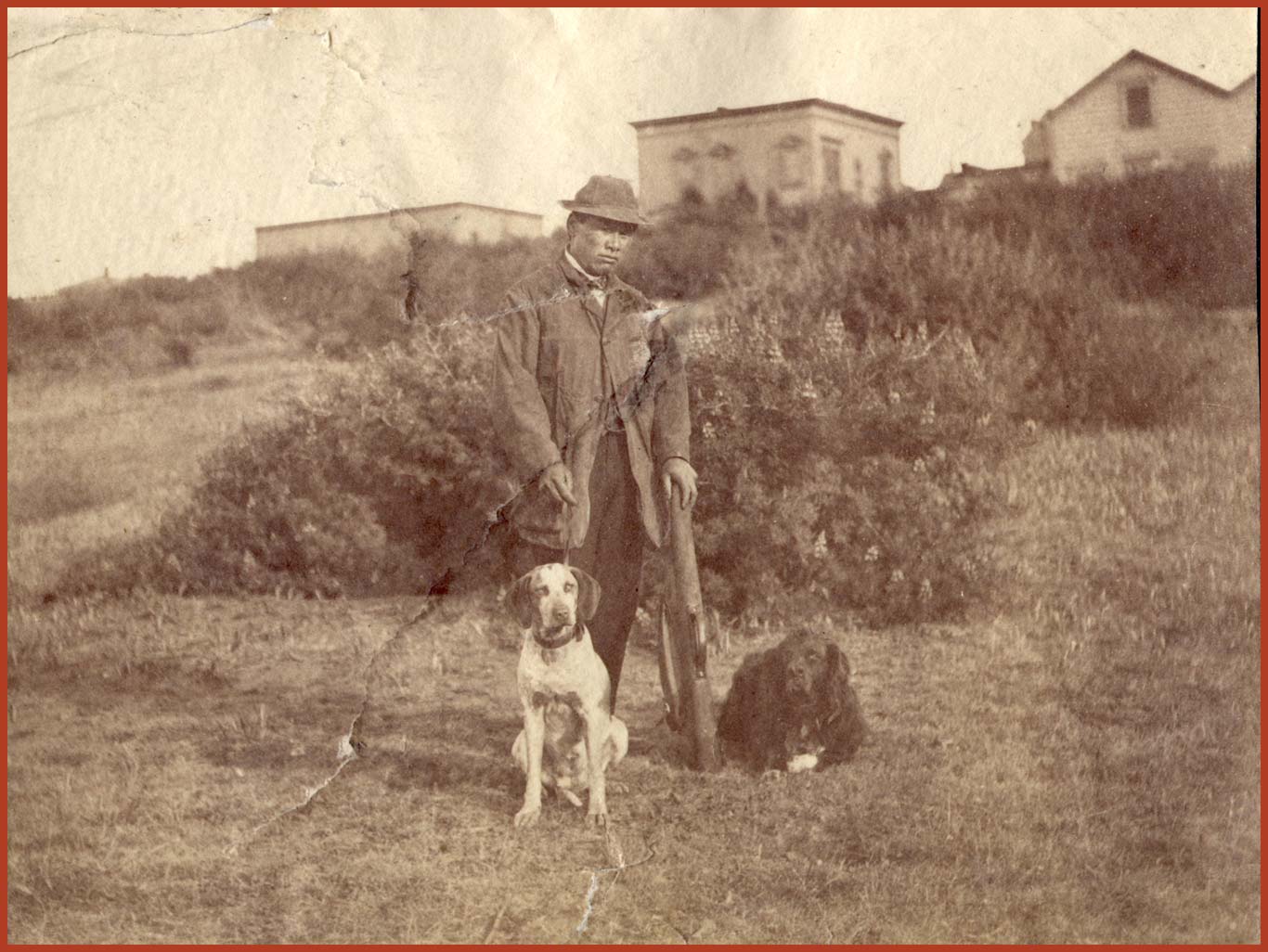 Joseph Tape with his hunting rifle and two bird dogs.