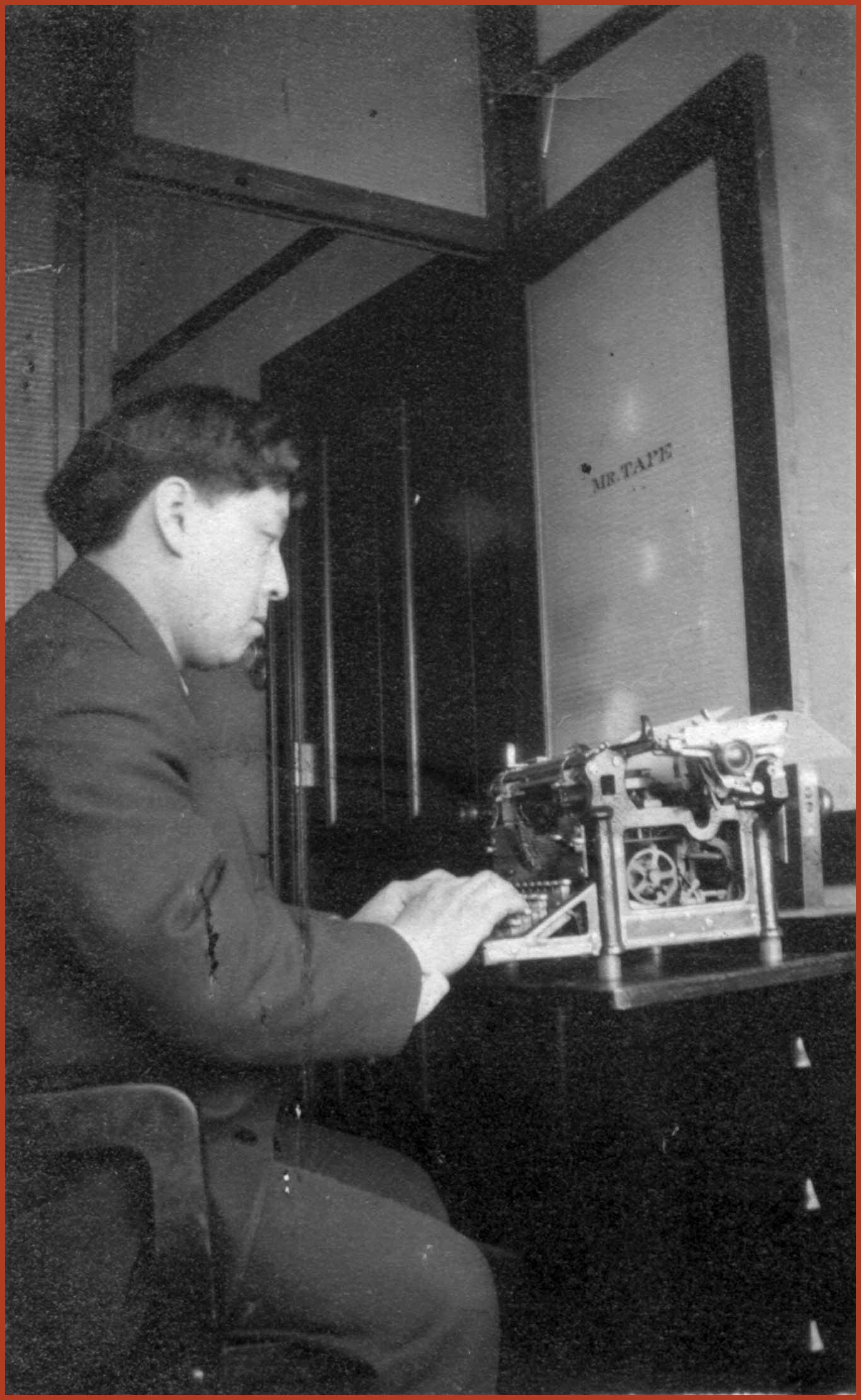 Frank Tape sits in his father's office, working at a typewriter. In the back the office door is open, upon the door is, "MR.TAPE."