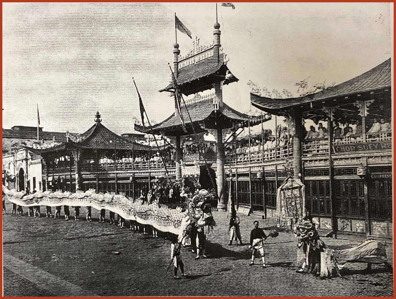 A line of lion dancers are in the foreground. In the background is a paifang, or a traditional chinese gateway.