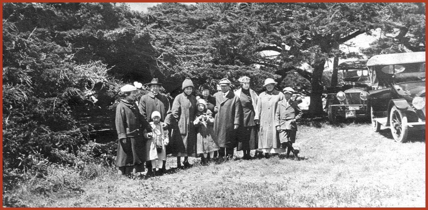 The Tape family gathers at Cypress Point for a family photo in a garden with 2 cars parked on the side. Left to right: Florence, Edward, and Winifred Park; Gertrude Chan; Bernice Park; Mary and Joseph Tape; Daisy Lee; Emily and Frank Park.