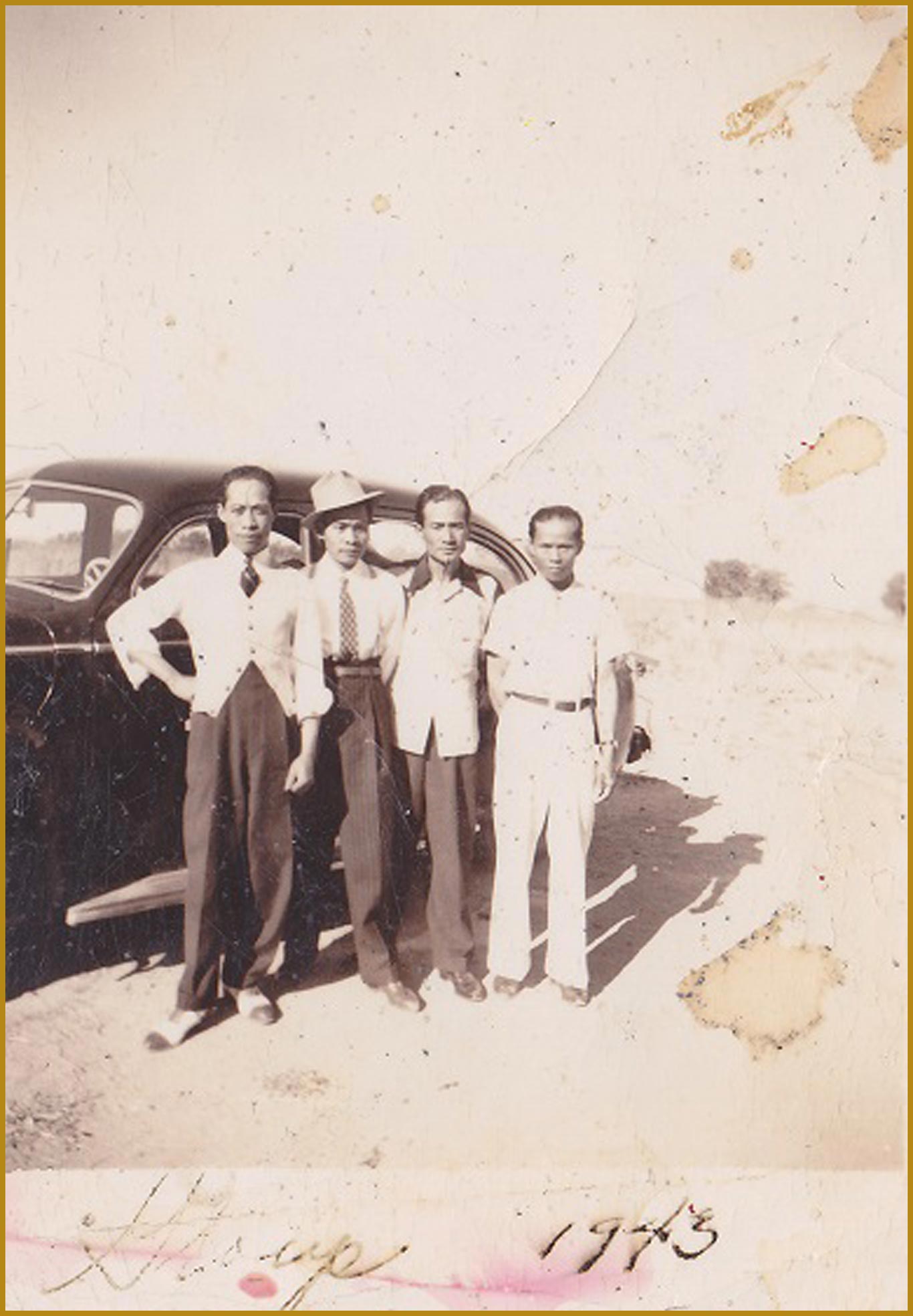 Filipino farmworkers posing in front of their car.