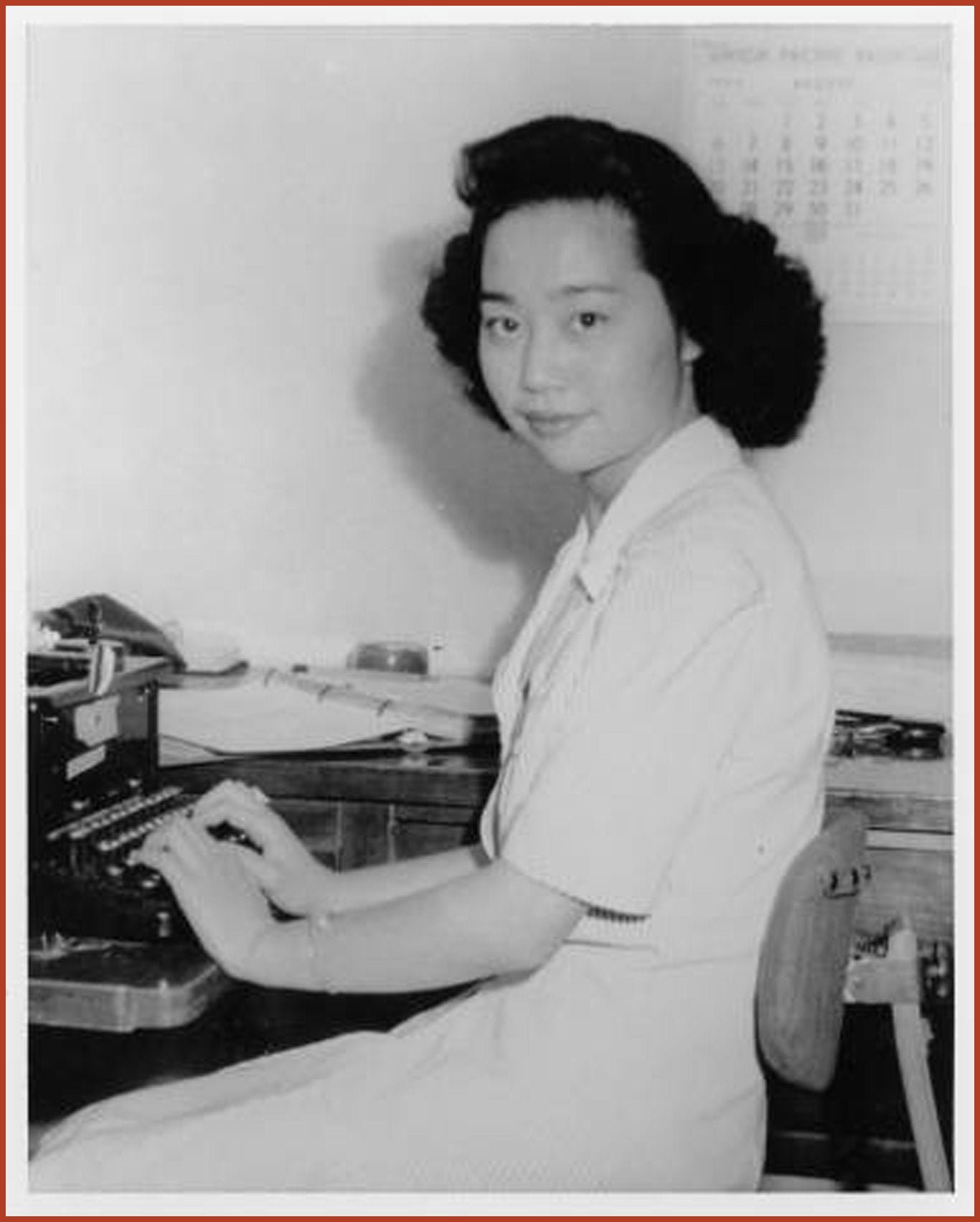 Mitsuye Endo sitting at a typewriter, turns to the camera.