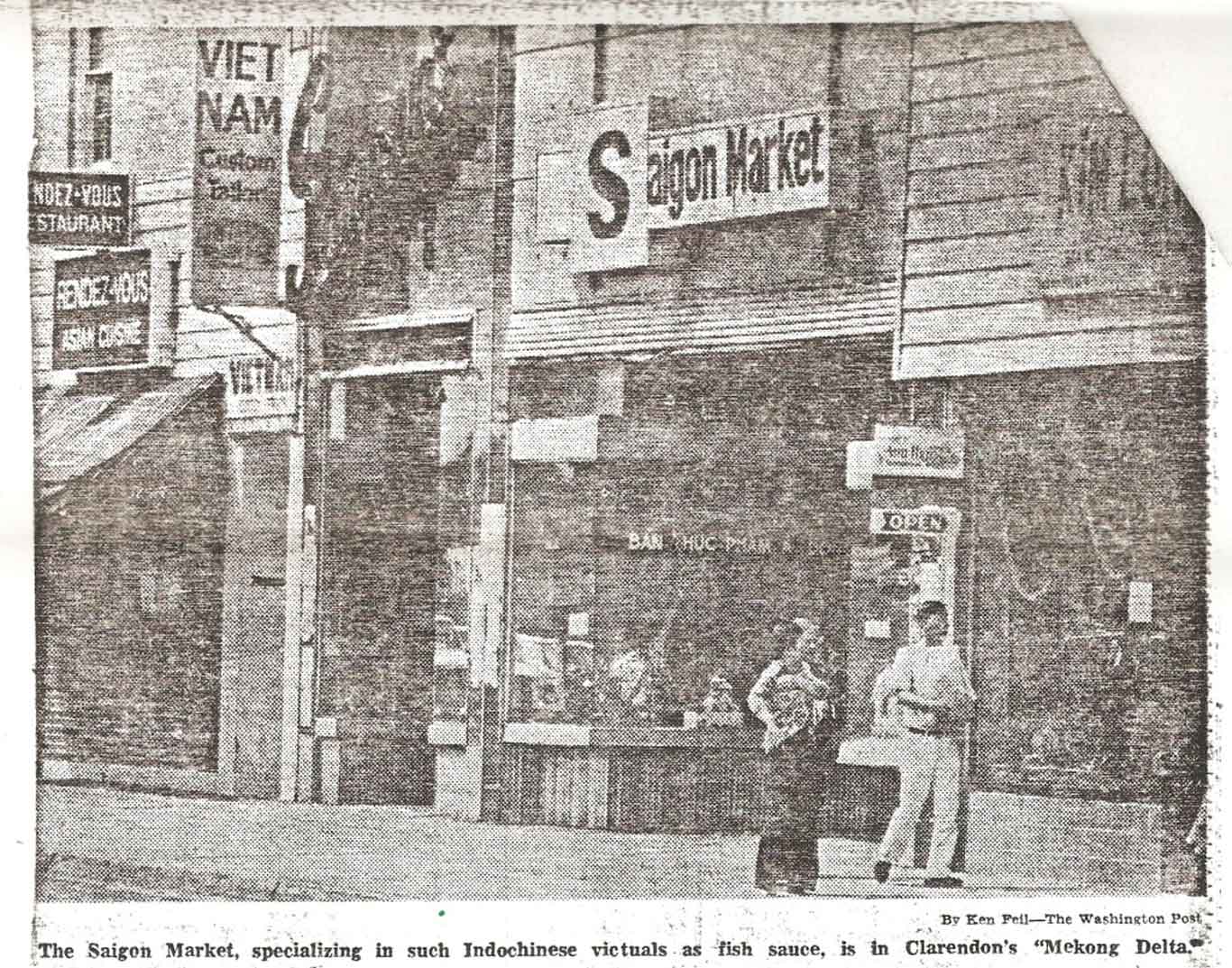 Black-and-white photo of a marketplace with individuals walking around. Sign reads "Saigon Market."