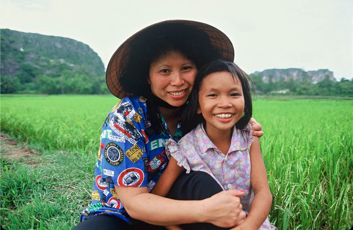 Le Ly Hayslip squats with a young girl in a rice field in her hometown, Ky La, in the Quang Nam-Da Nang Province.