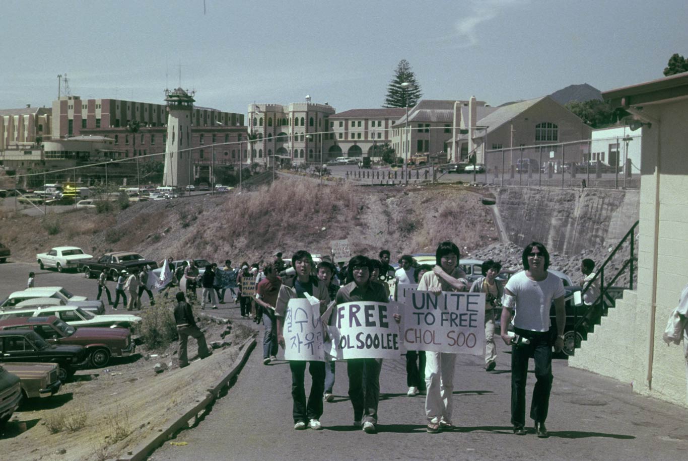 Protesters march up a street holding signs that say "Free Chol Soo Lee."