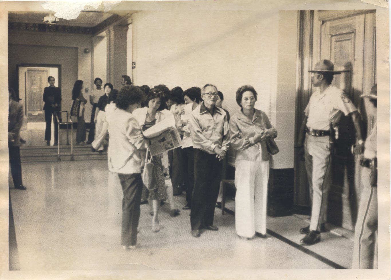 Chol Soo Lee supports line up outside of the courtroom. Two police officers guard the door.