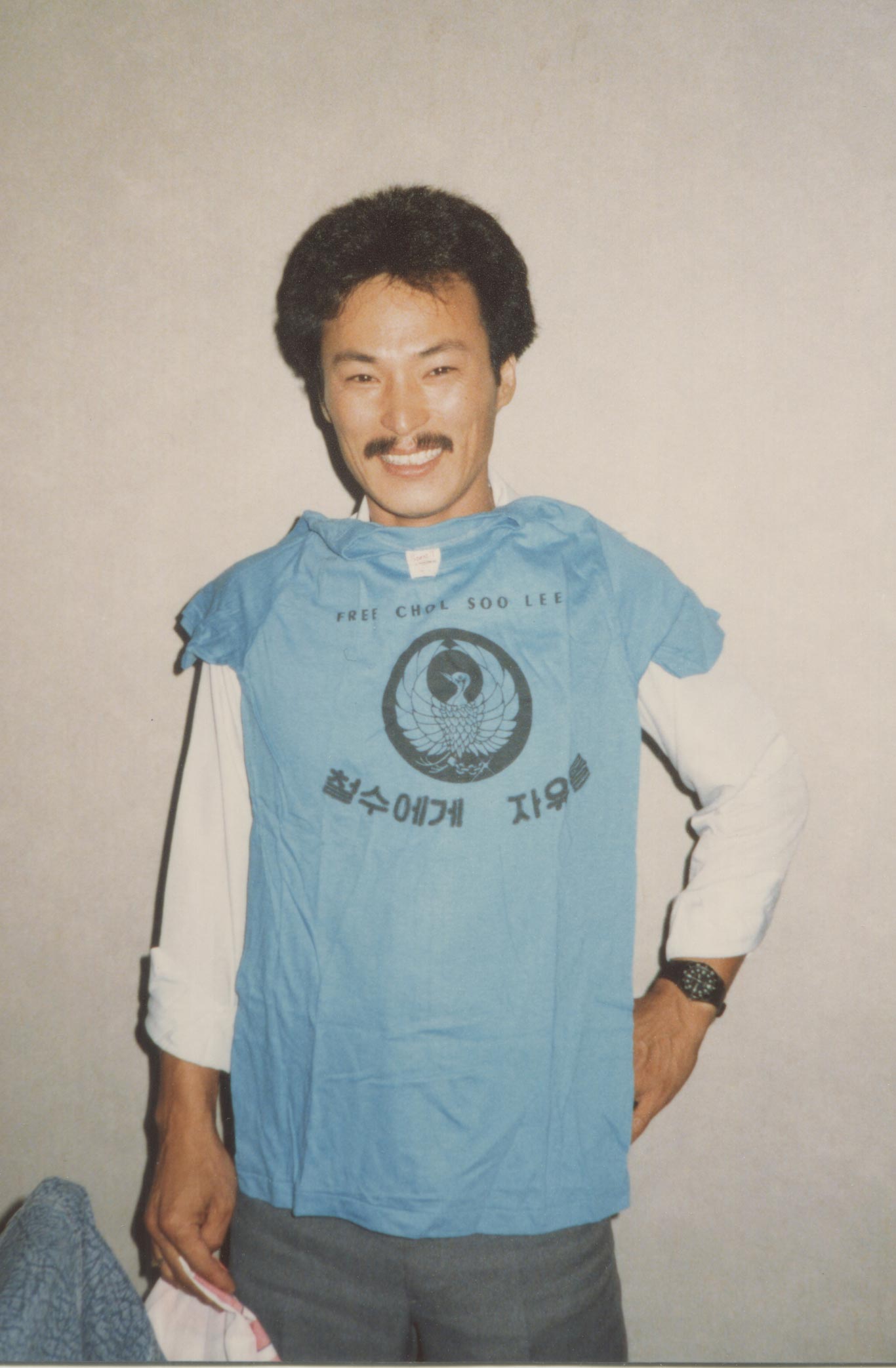 Chol Soo Lee stands while wearing a shirt that says "Free Chol Soo Lee."