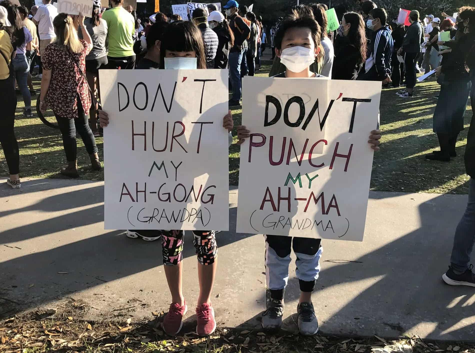 Nancy and Michael Liu wearing masks hold up signs that read "Don't hurt my Ah-gong/Ah-ma" at a rally against Asian discrimination and violence.