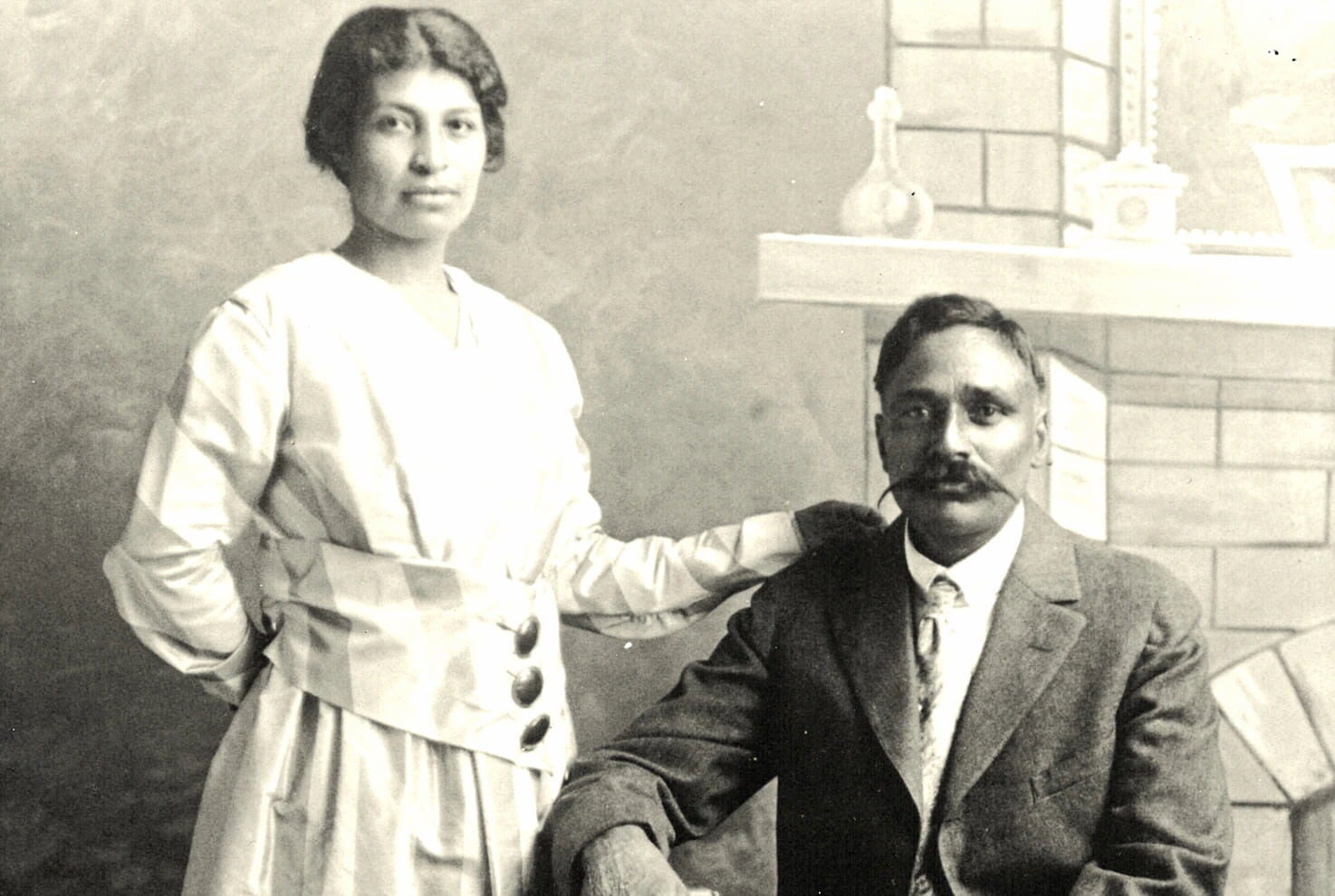 Portrait of a Punjabi Mexican American couple, Valentina Alvarez standing on the left and Rullia Singh sitting on the right, in their wedding attire.