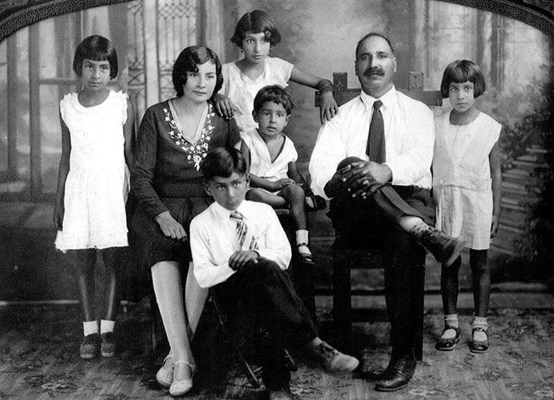 Family portrait of Punjabi Mexican couple Ernestina and Bishan Singh seated with their three daughters and two sons placed between them.