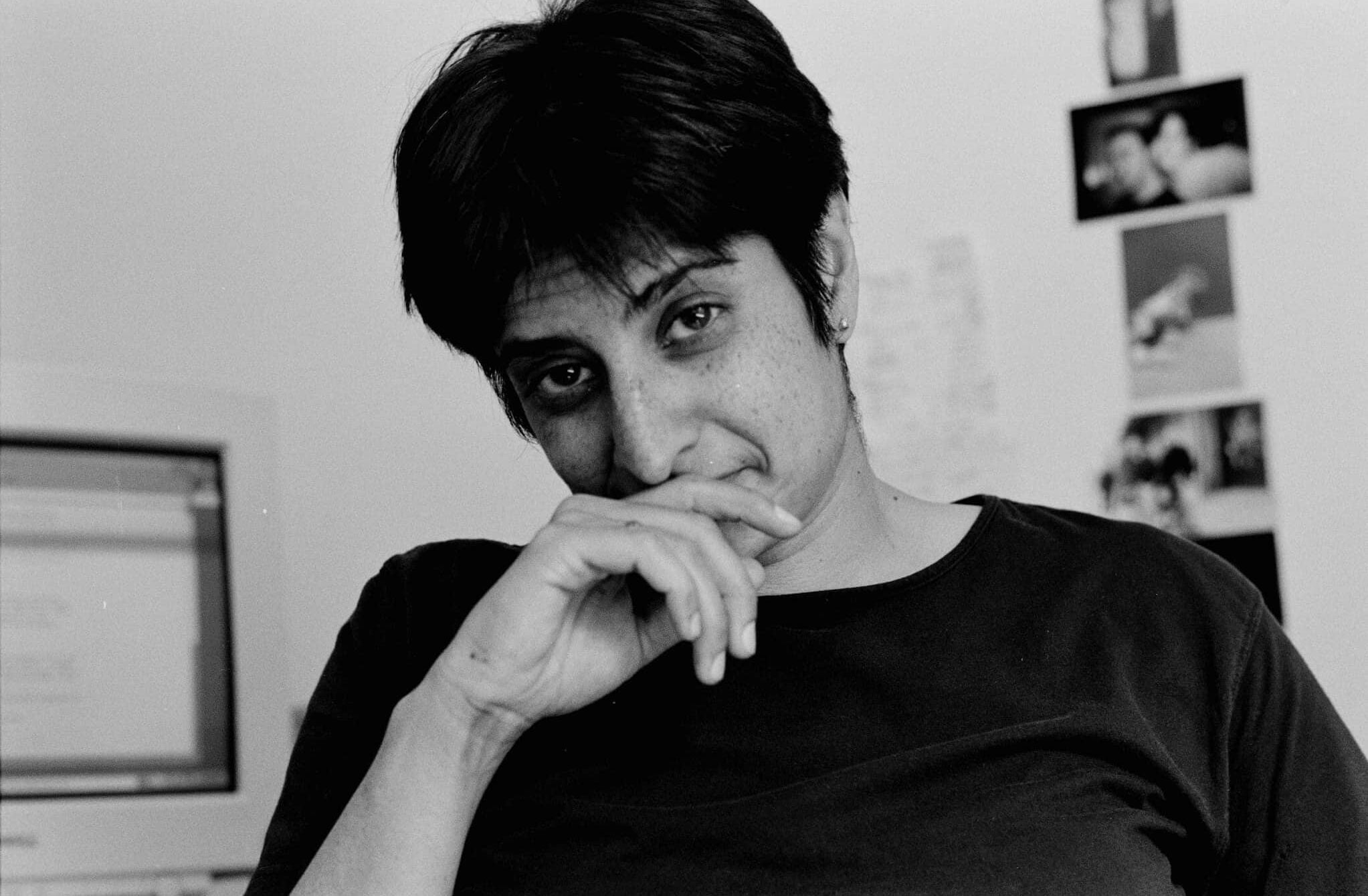 Indian American activist Urvashi Vaid dressed in a back t-shirt and holding her right hand against her mouth.