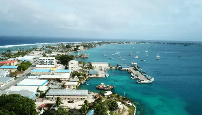 Aerial photo of Majuro, a narrow strip of land surrounded by ocean on either side. Low-rise buildings surround street, with trees dotting landscape.