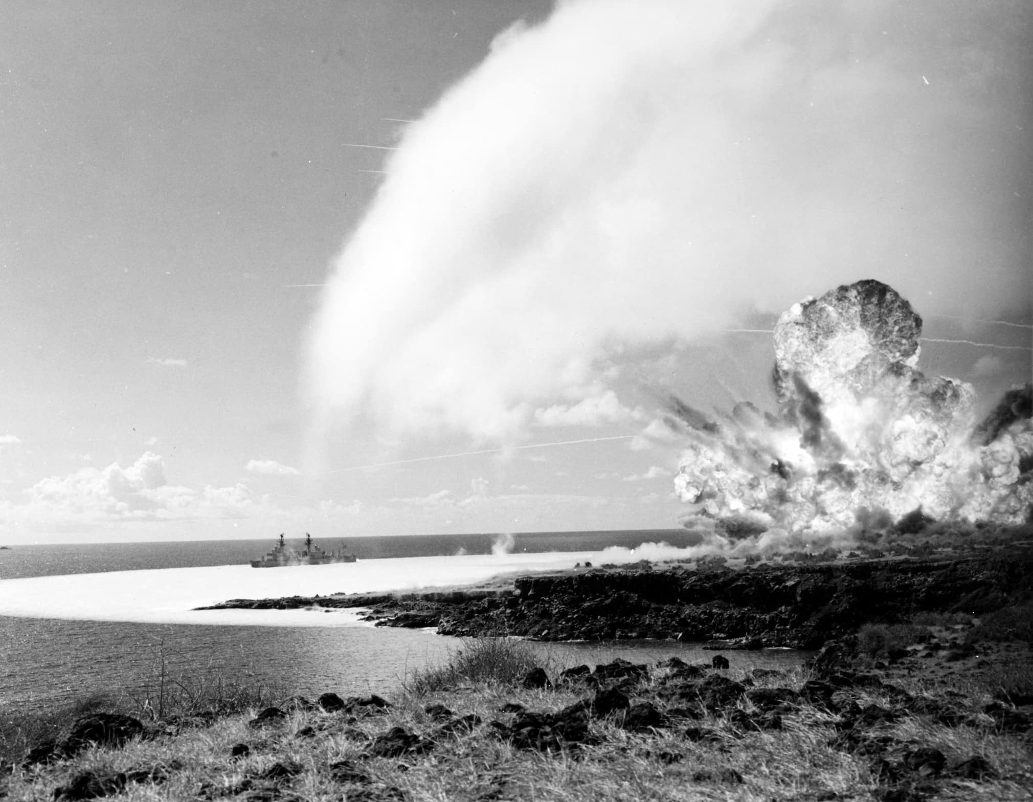 A condensation cloud forms above the detonation of 500-tons of TNT on Kaho‘olawe. A shockwave spreads over the water towards a U.S. Navy test ship.