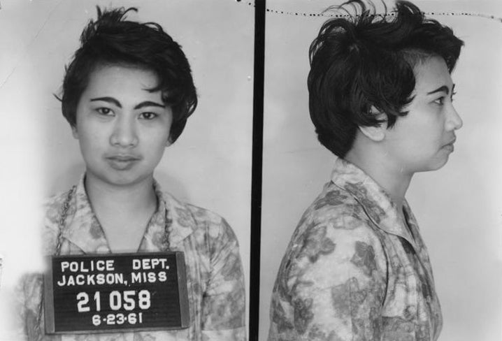 Mugshot of Mary Harrison Lee, wearing a floral print dress with short hair and the mugshot board around her neck.