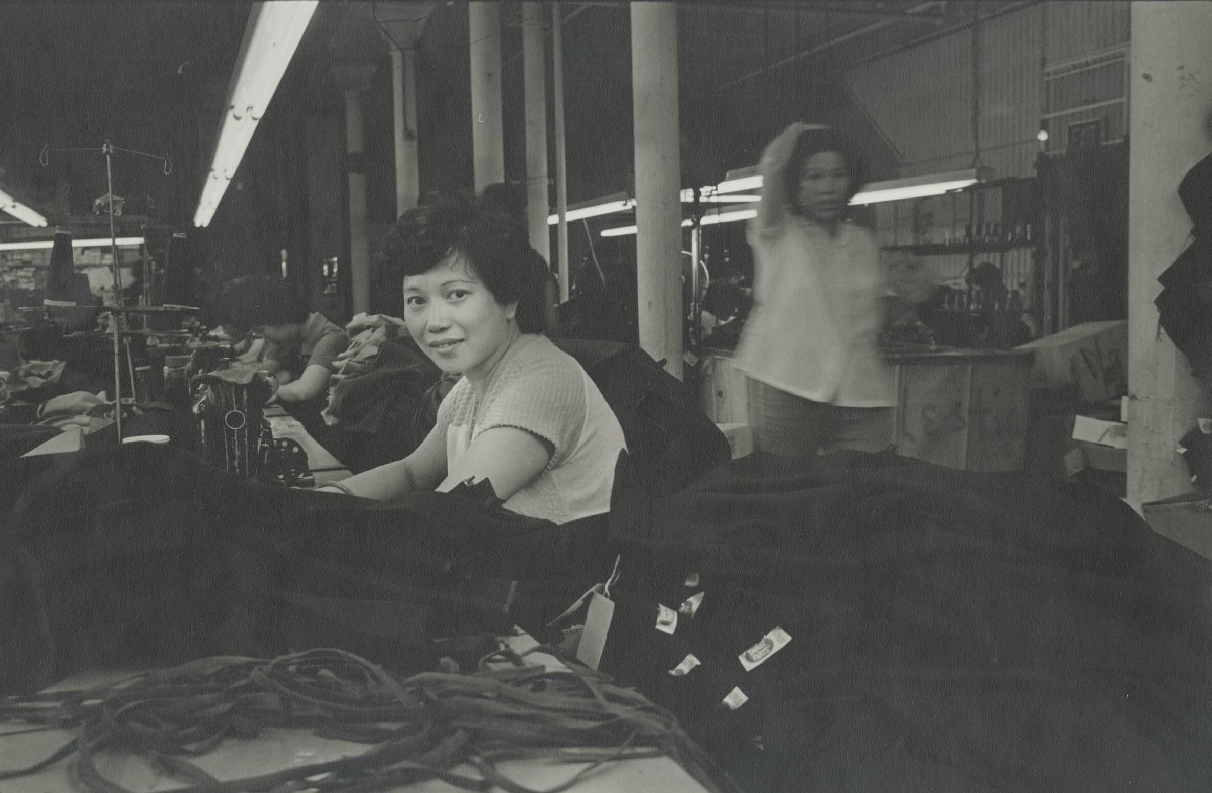 Woman seated at work station in garment factory.