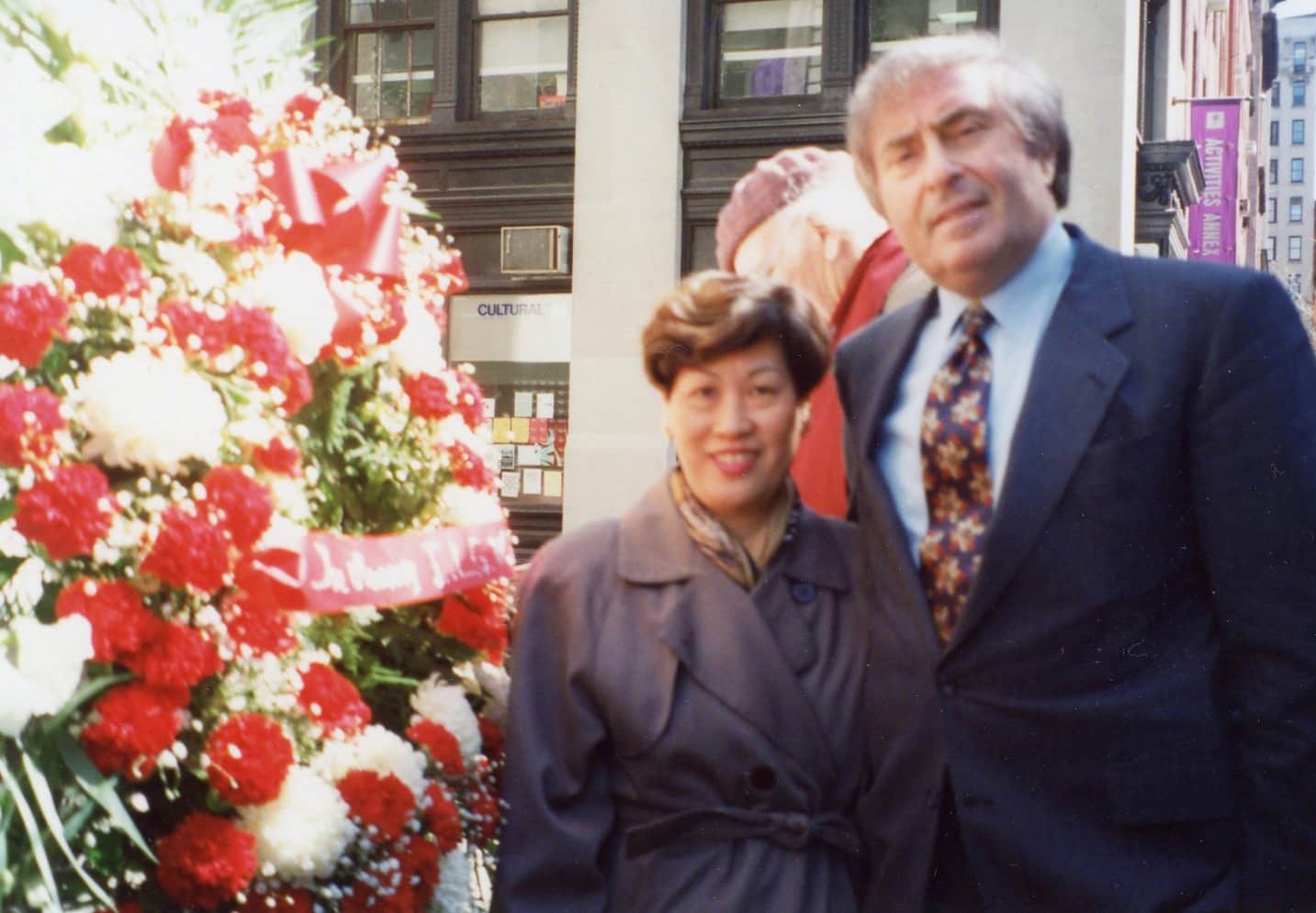 Alice Ip, retired garment worker and union organizer, with Jay Mazur, man in suit. They stand beside wreath at Triangle Fire Memorial.