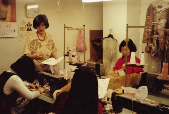 Labor organizer May Chen stands and distributes leaflets to workers seated in front of their work stations.