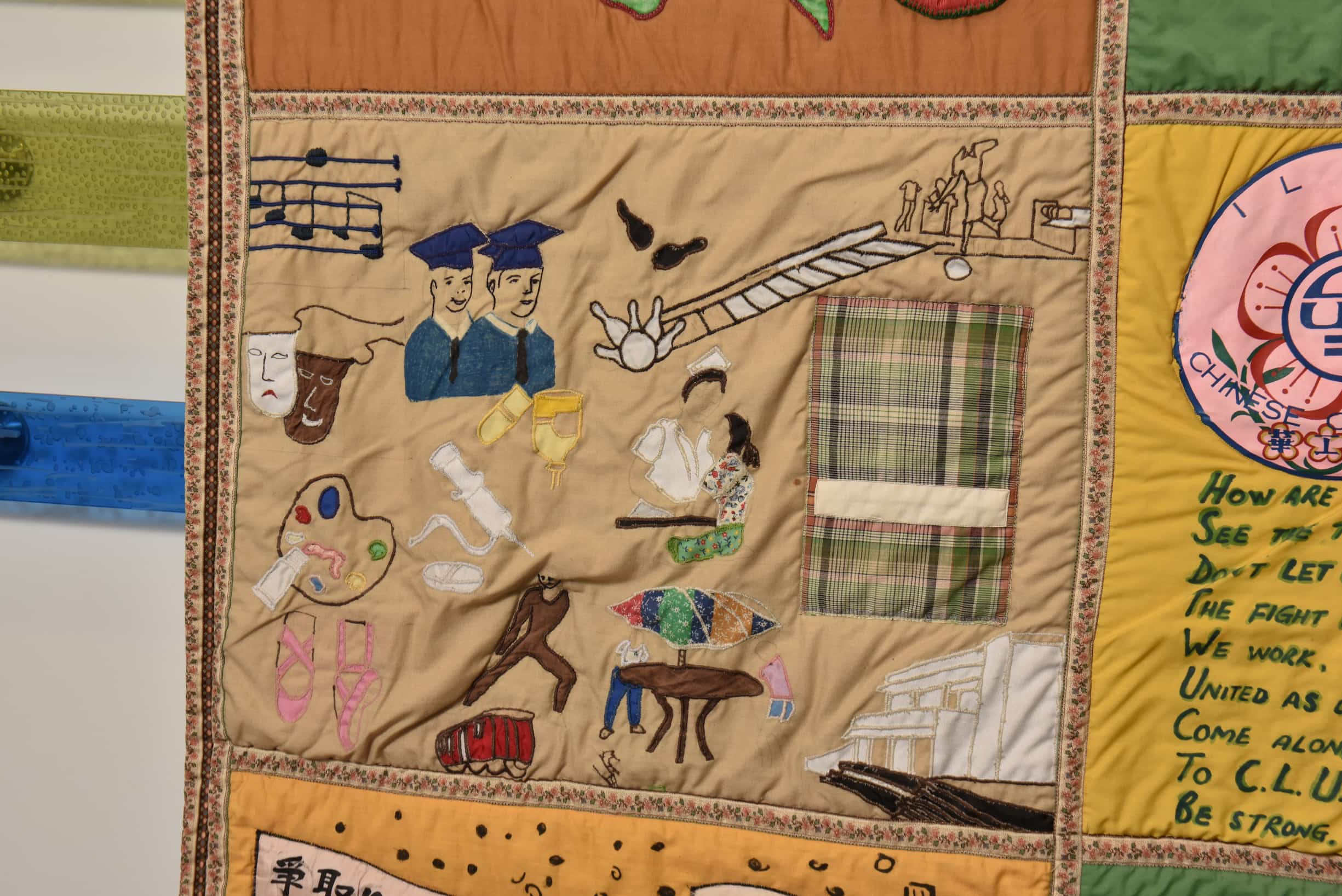 Close up on quilt square with tan background. Icons representing dancing, theater, music, and bowling are present.