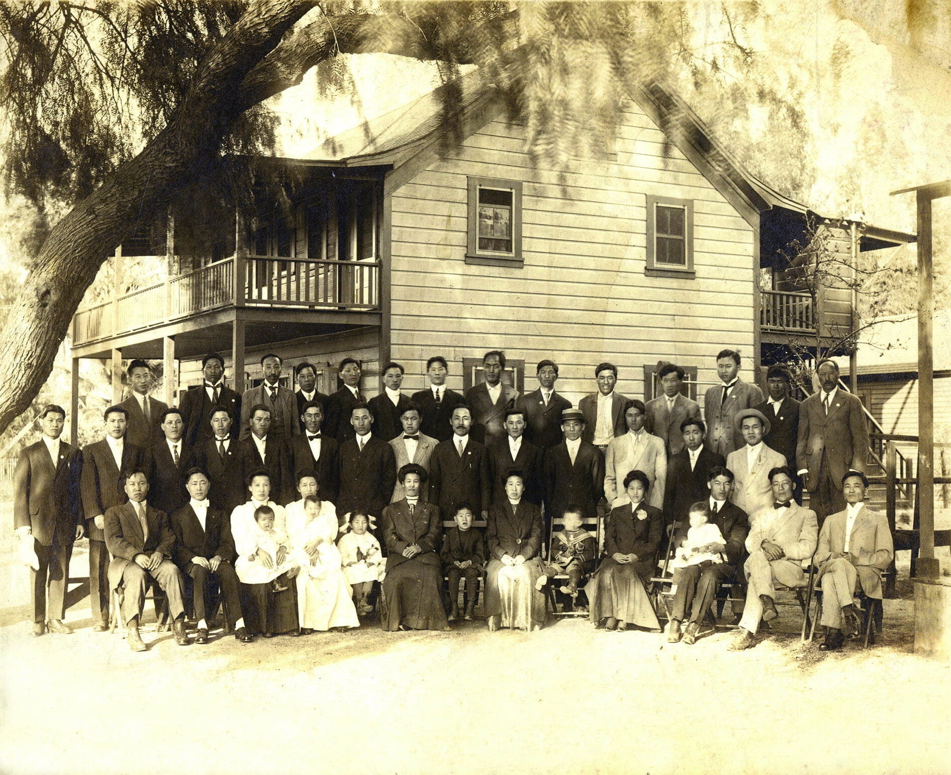 Group of Korean men, women, and children pose for group photo in front of building.
