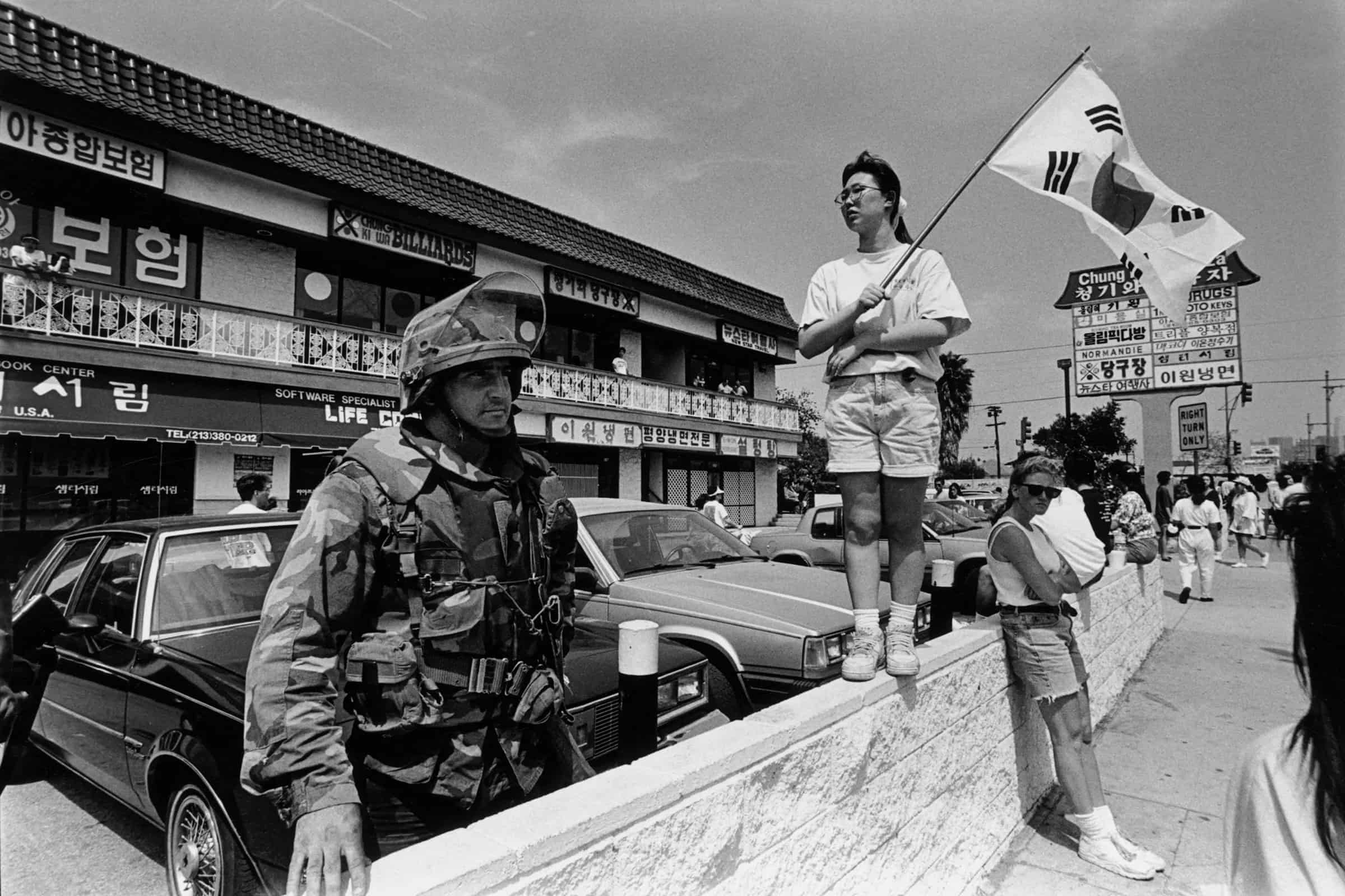 Woman carrying South Korean flag stands next to member of the National Guard following the 1992 Los Angeles Uprising.