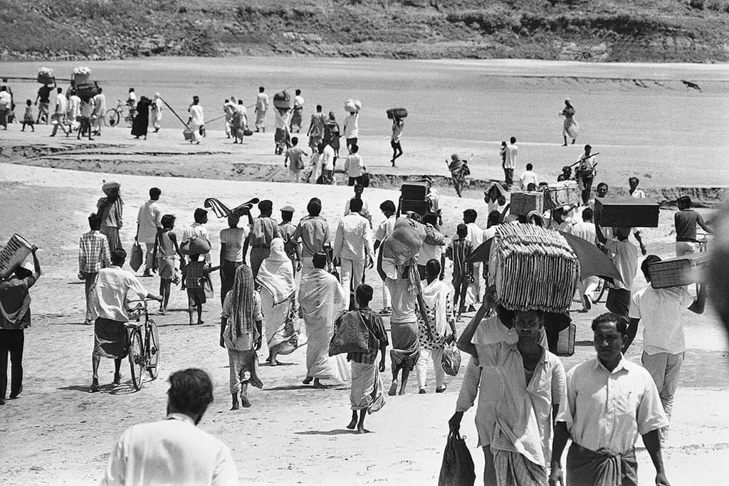 Refugees carry their belongings while trekking across a dry riverbed in the Ganges Delta at Kushtia.