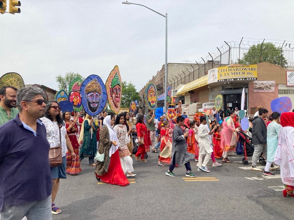 Bangladeshi Americans dressed in salwar kameez, kurta, and panjabi parade through the streets carrying colorful handmade masks during Pohela Boishakh.