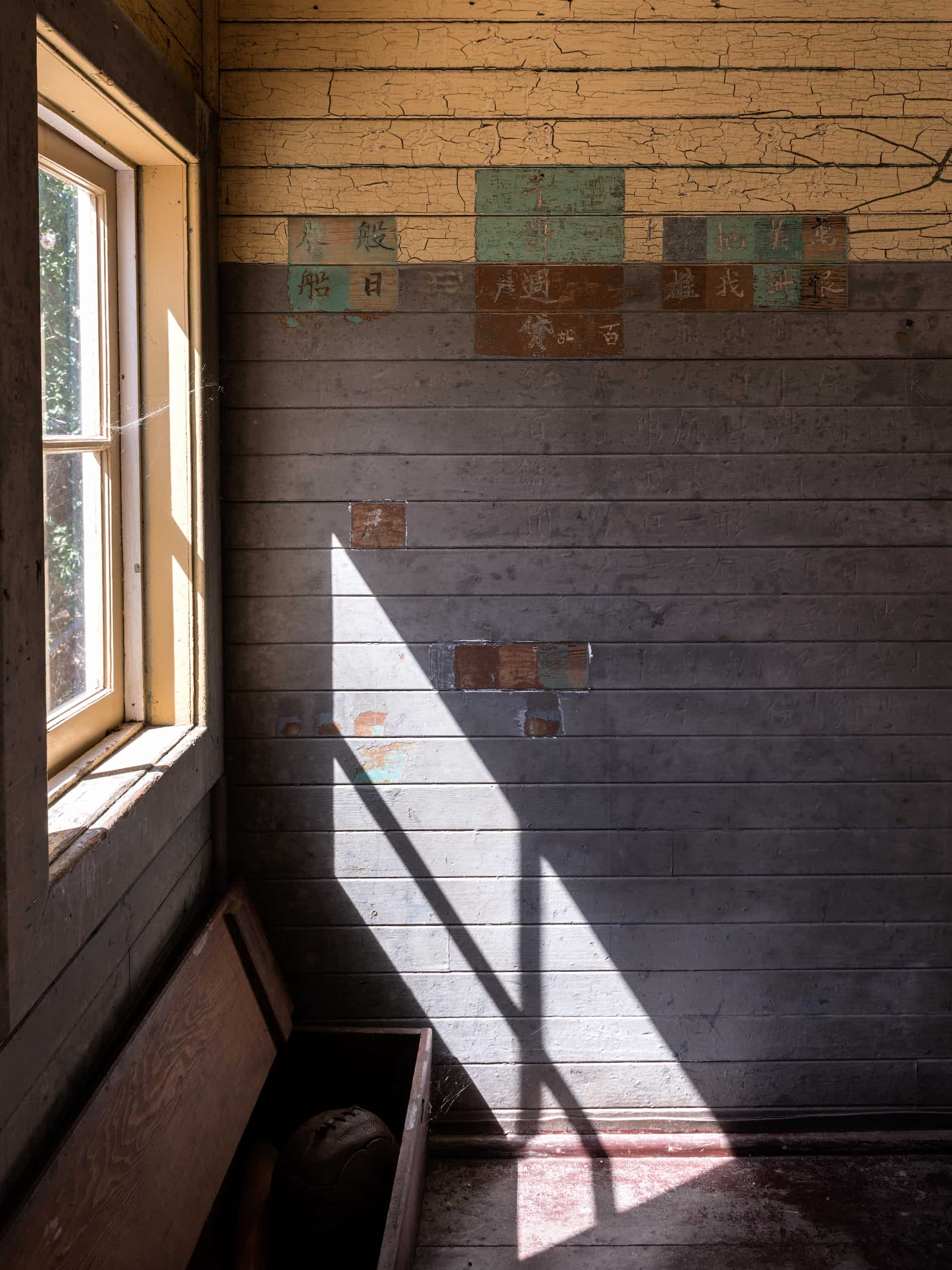 Interior of Angel Island Immigration Station. Poems carved into the wall by detained Chinese immigrants are visible and a window lets the sunlight in.
