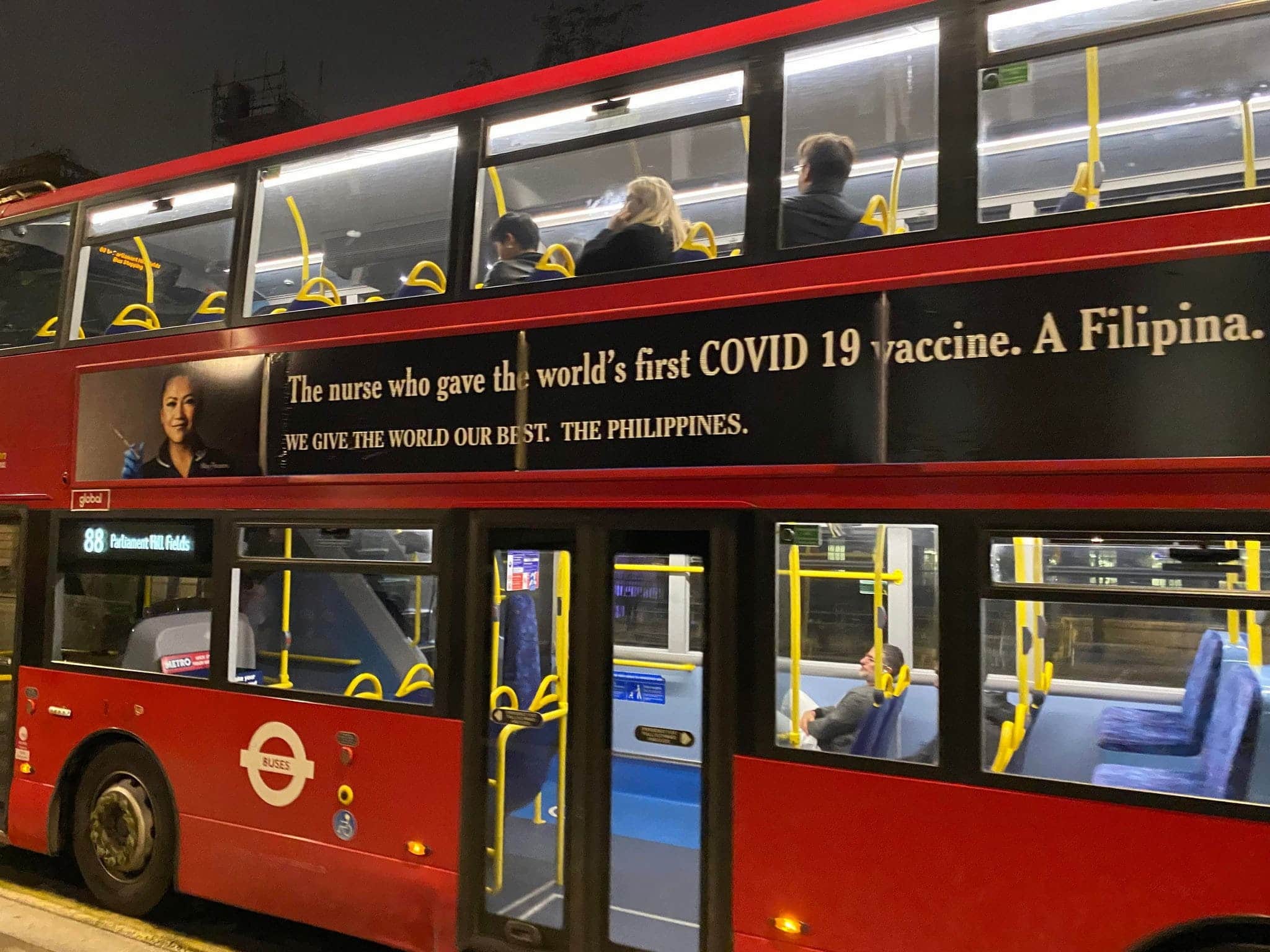 Double decker bus ad says "The nurse who gave the world's first COVID 19 vaccine. A Filipina. WE GIVE THE WORLD OUR BEST. THE PHILIPPINES."