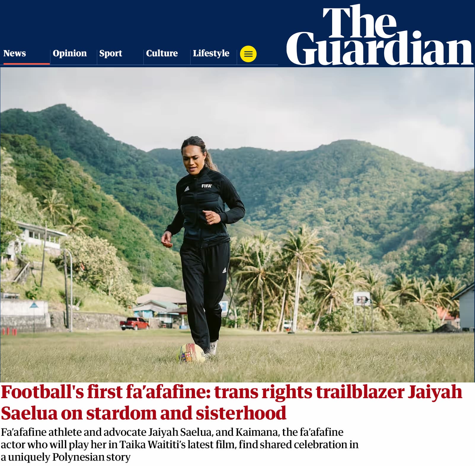 Samoan American Jaiyah Saelua, dressed in athletic wear, kicks a soccer ball on a grassy field surrounded by mountains.