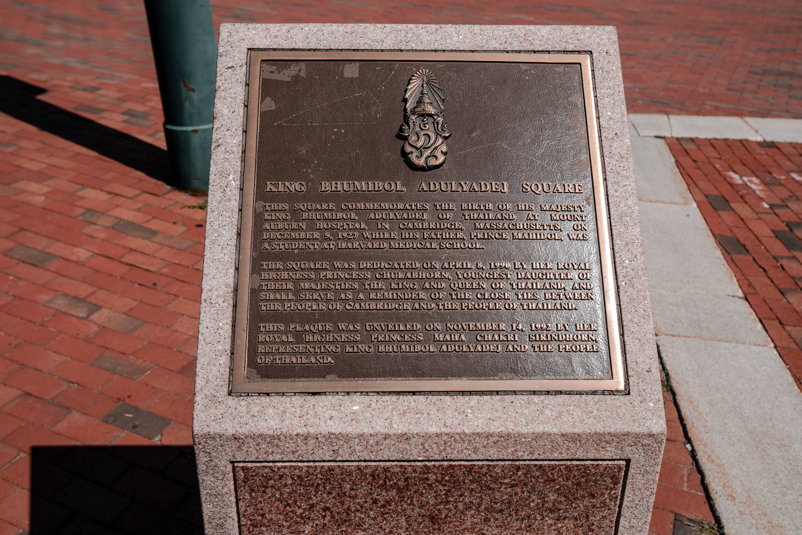 Monument honoring King Bhumibol's birthplace. Bronze plaque has text related to King Bhumibol beneath decorated symbol.