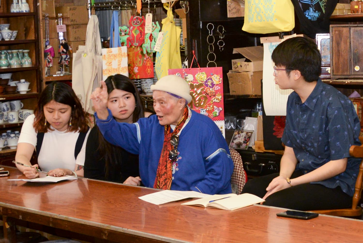 Union activist Shui Mak Ka, in blue jacket, raises hand as she speaks to crowd while seated at table.
