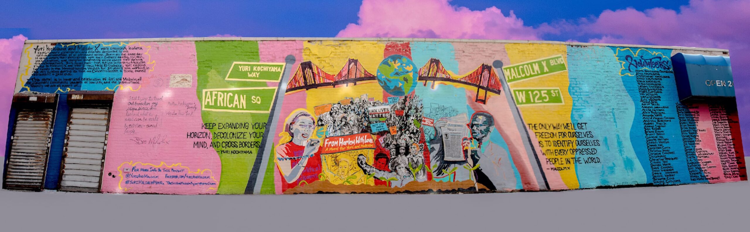 Photo of colorful outdoor mural featuring illustrations of Yuri Kochiyama, Malcolm X, and other activists. Behind mural is a sky full of pink clouds.