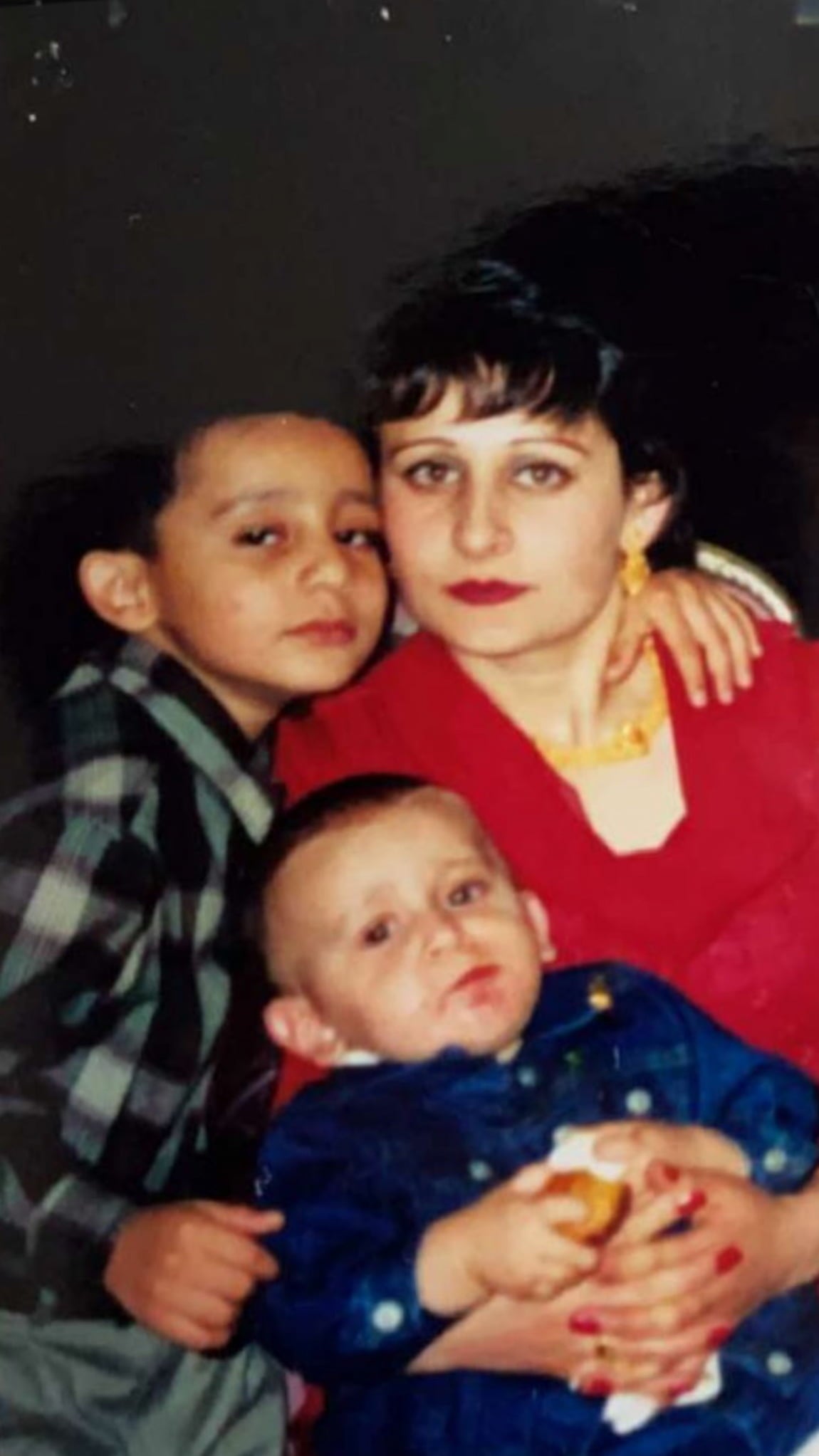 Posing for the camera, Sharifa Zaman hugs her young son to her chest while her older son has an arm wrapped around her shoulders.