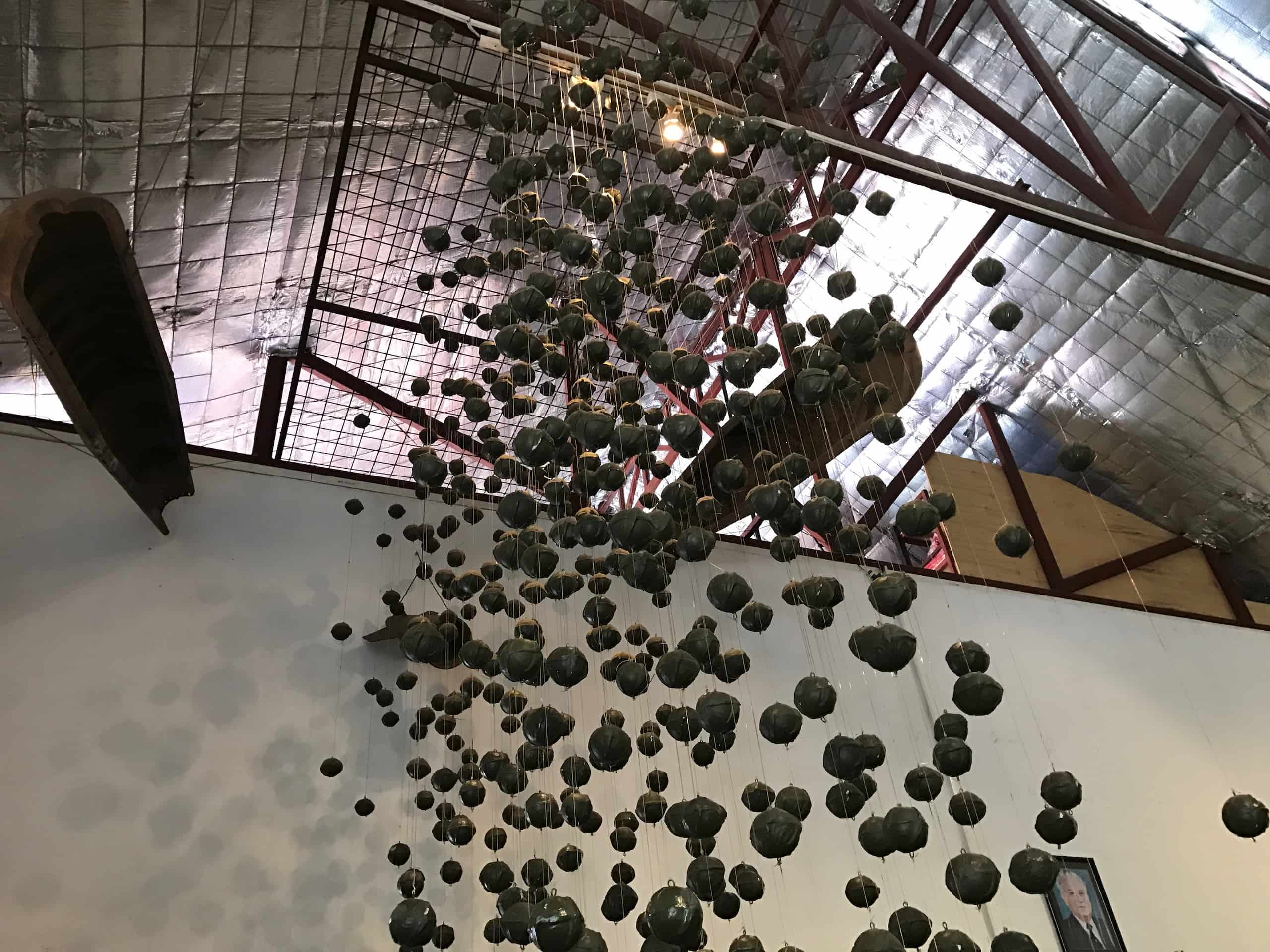 Museum display shows a cluster bomb opening in mid-air with each bomb suspended by long strings hanging from the ceiling.