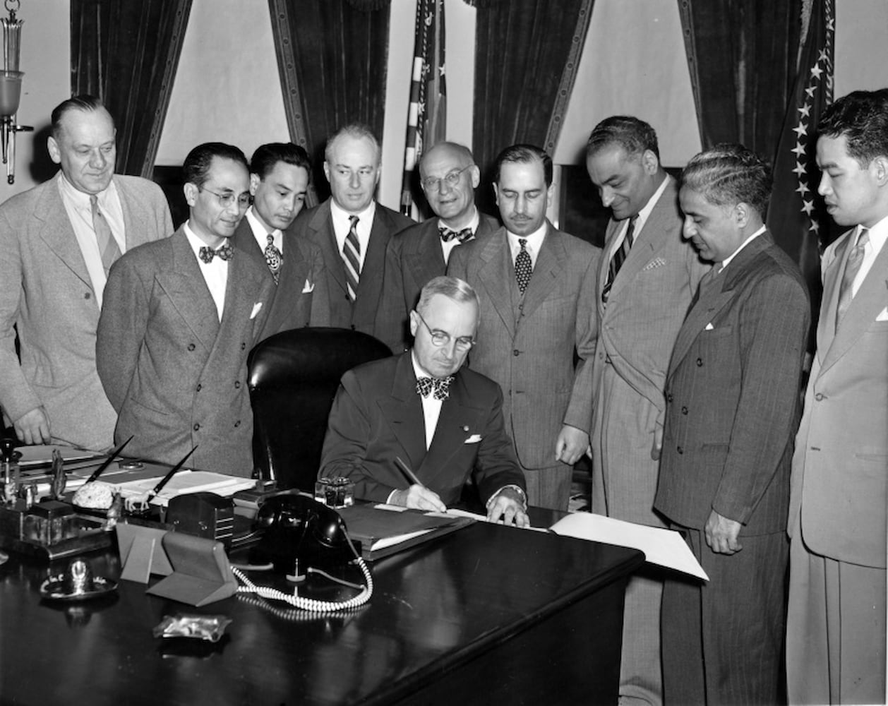 Sikh merchant Jagjit Singh stands alongside U.S. government officials witnessing a seated President Truman as he signs the Luce-Celler Act of 1946.