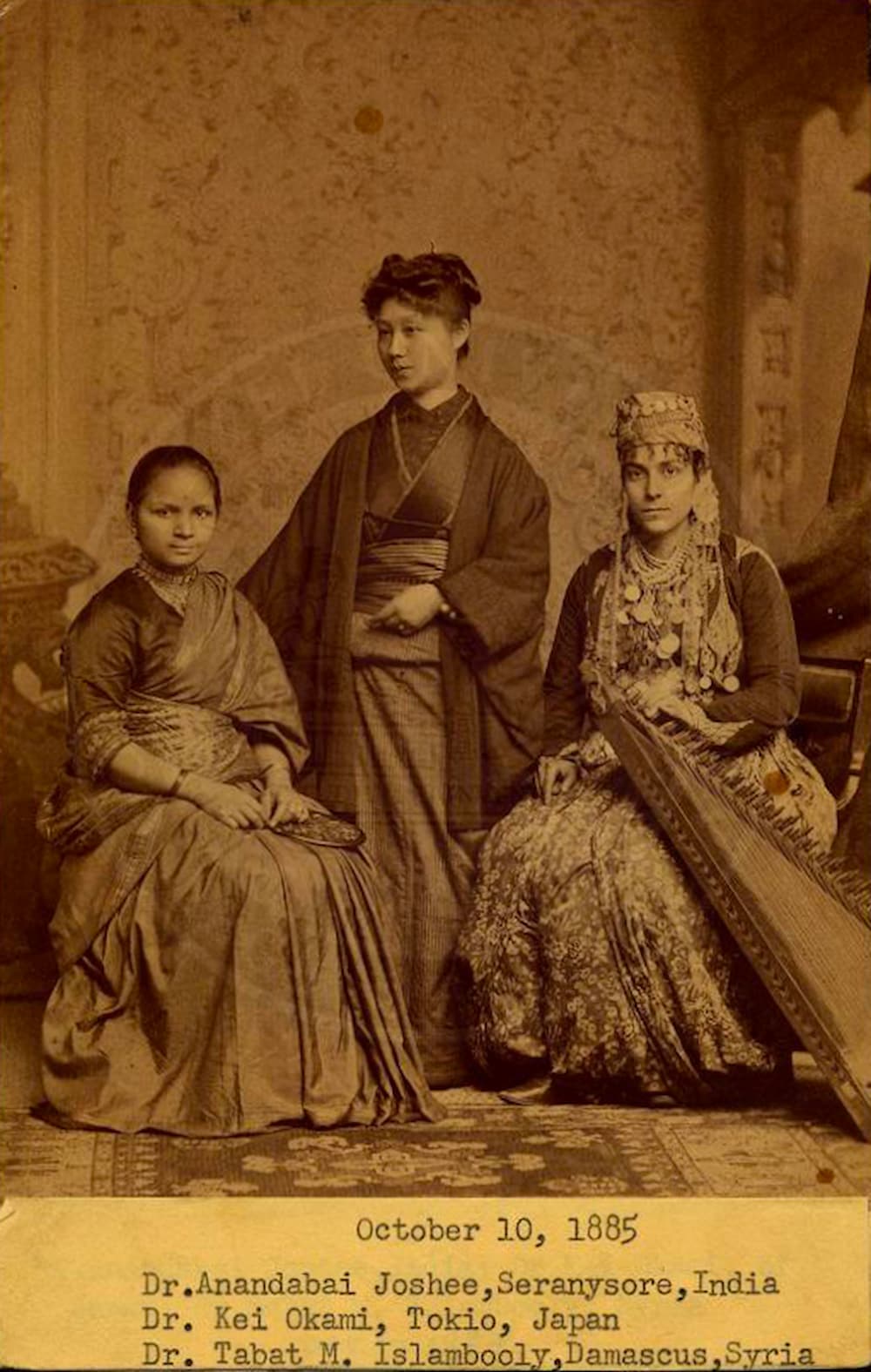 Portrait of three female doctors. Dressed in a saree, Anandibai Joshee sits beside classmates, Kei Okami from Japan and Sabat Islambouli from Syria.