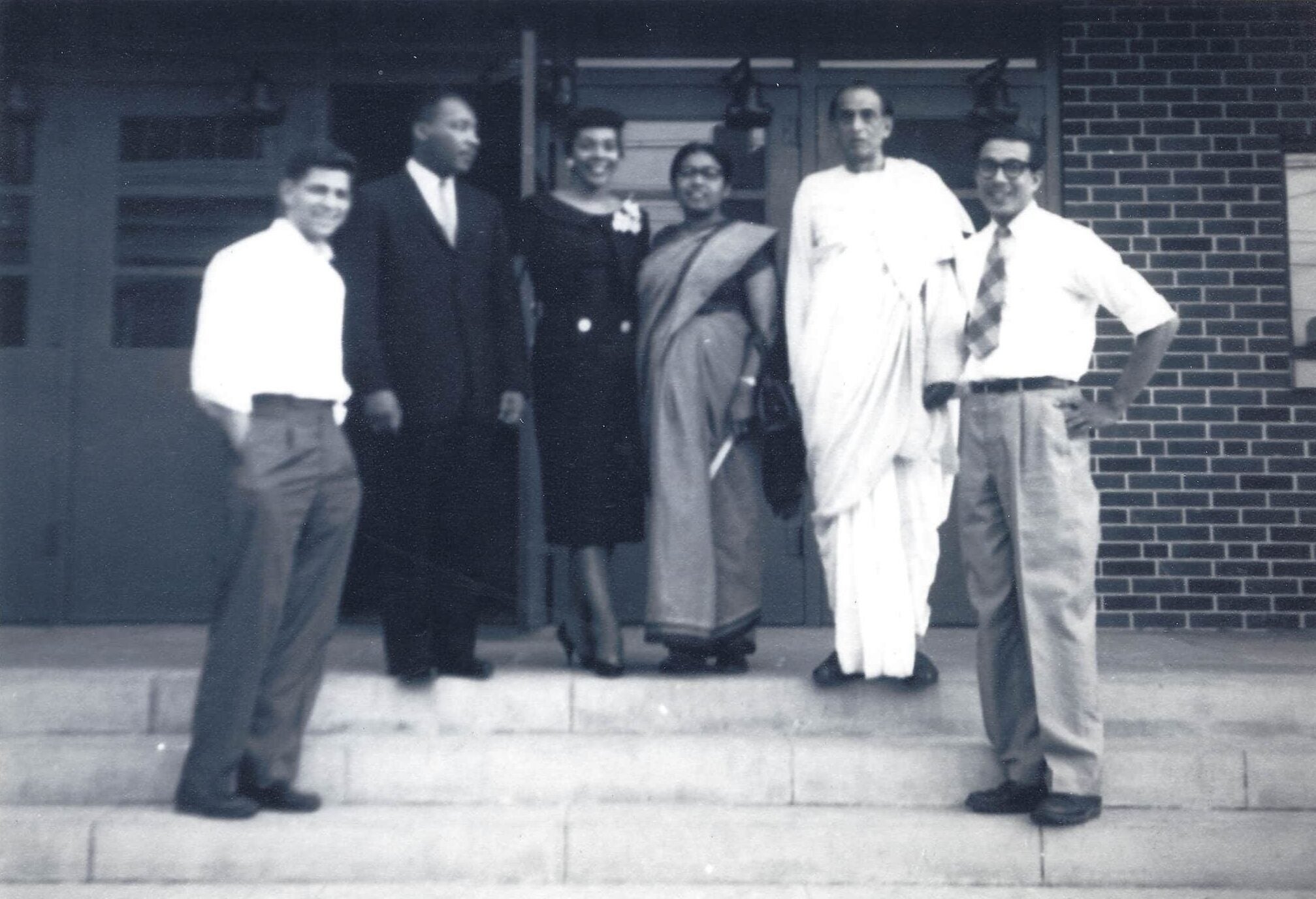 Two MIT students stand on a lower step and on either end of Dr. Martin Luther King, Jr., Coretta Scott King, and Acharya and Sucheta Kripalani.