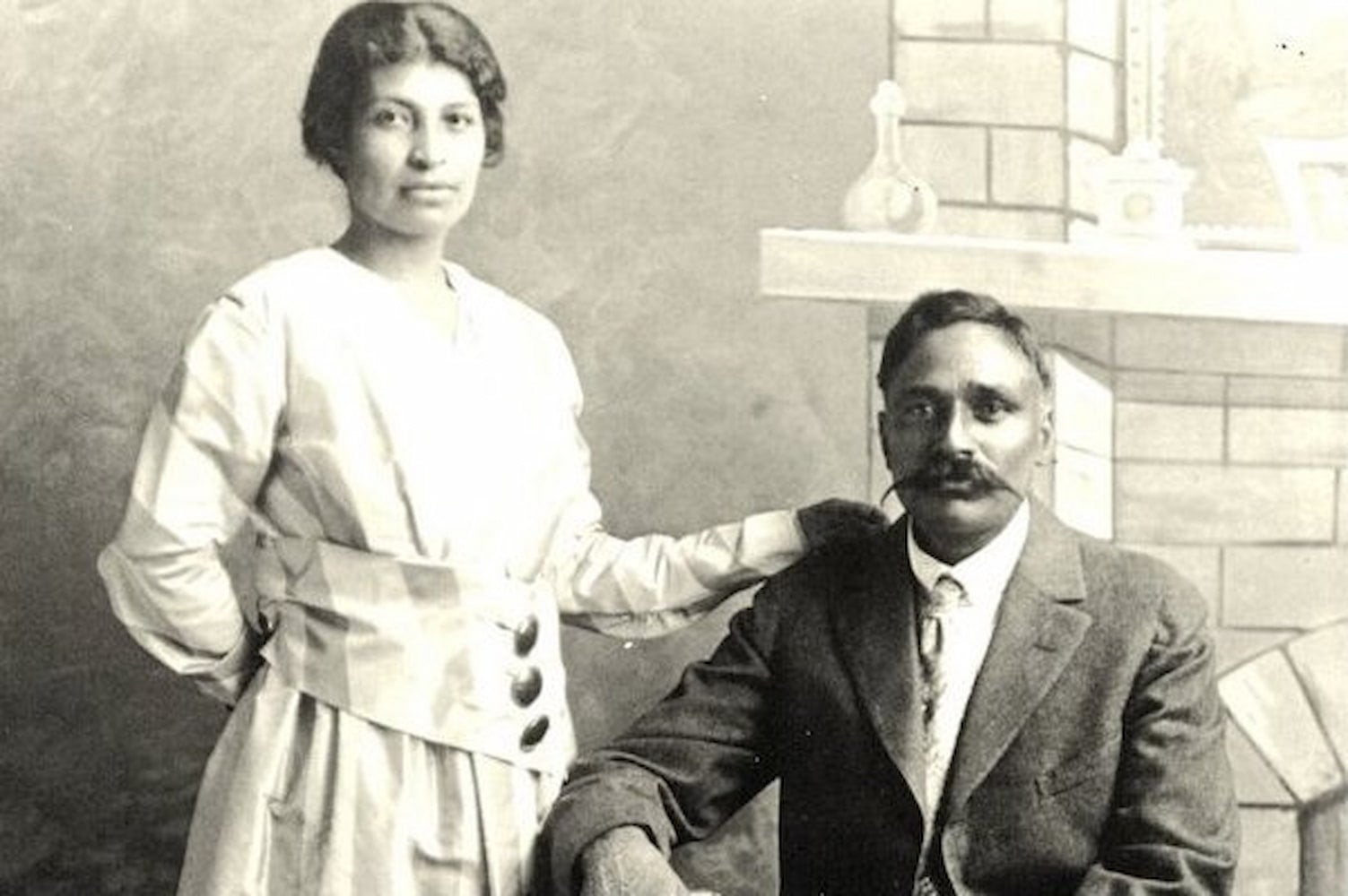 Portrait of a Punjabi Mexican American couple in their wedding attire. Valentina Alvarez stands on the left and Rullia Singh sits on the right.