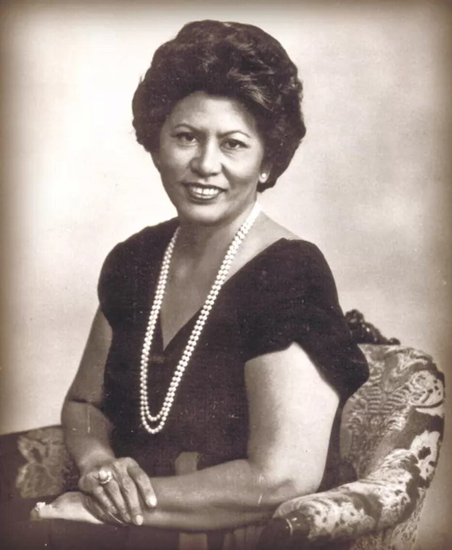 Portrait of CHamoru Cecilia Bamba seated in an armchair. She wears a cap sleeved dress and a double strand pearl necklace.