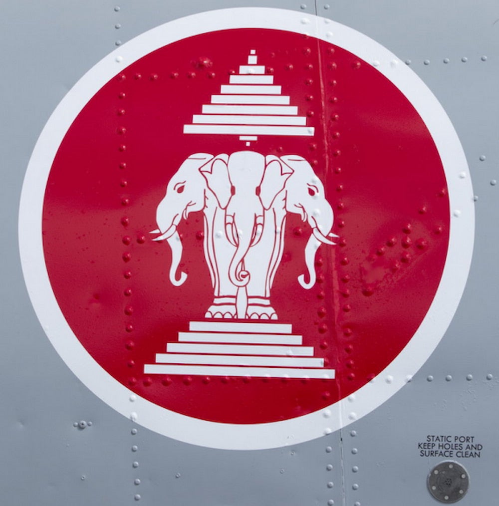 A red and white roundel featuring elephants affixed to a gray airplane.