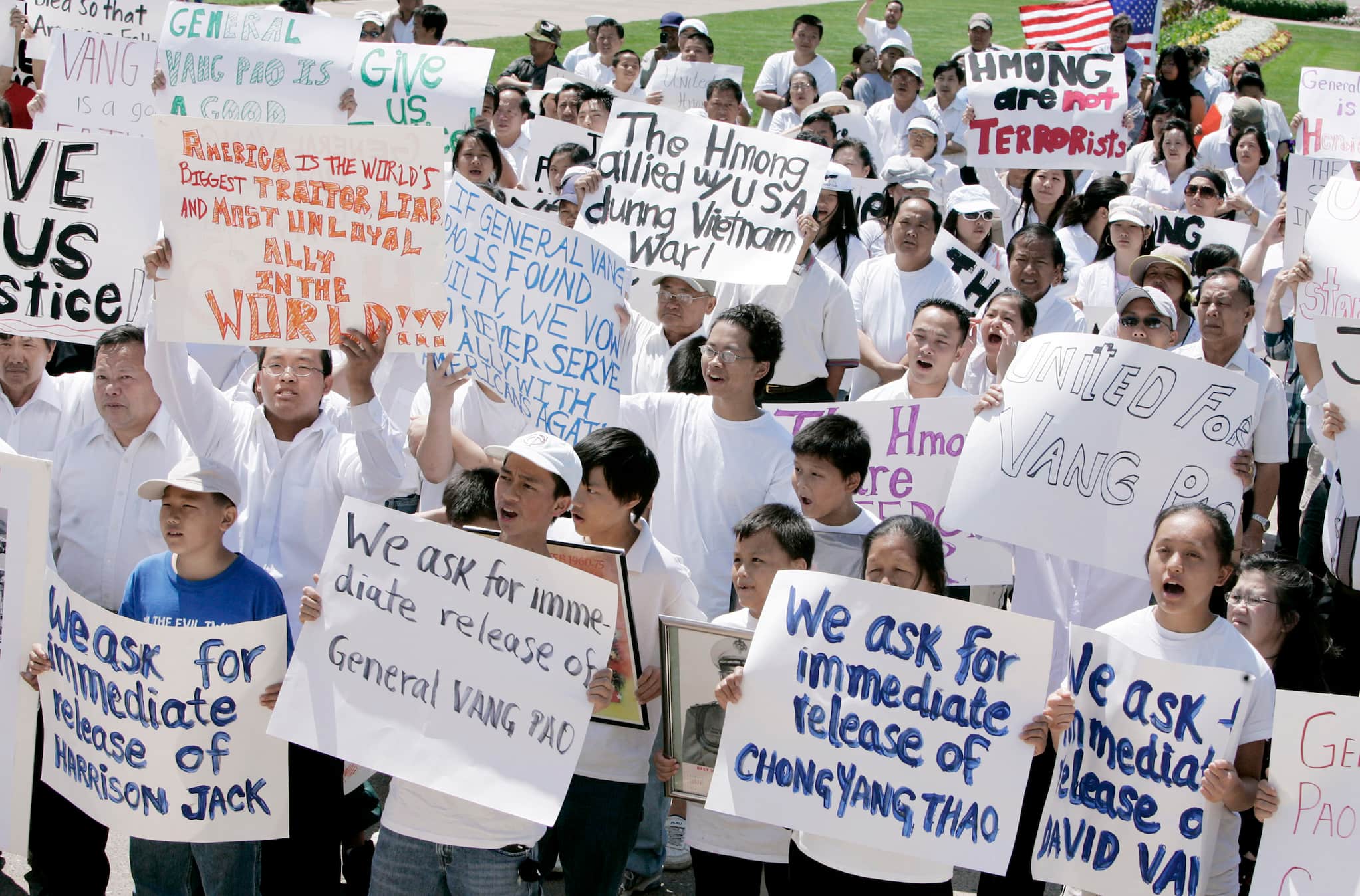 Hmong community members hold signs demanding the release of General Vang Pao during outdoor rally.