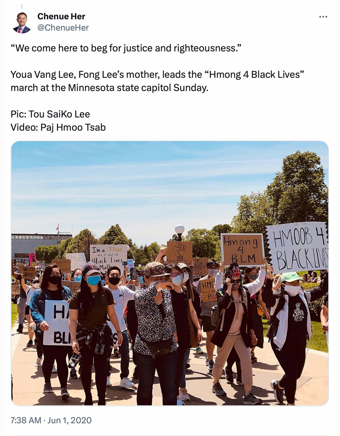 Youa Lee, in a black and white patterned shirt and a face mask, leads a group of people as they march outside during Justice for George Floyd protest.