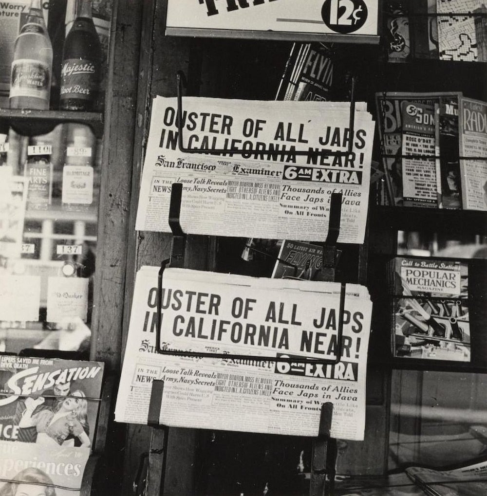 At a newspaper stand, headlines read, "Ouster of all Japs in California Near!" On display around it are various magazines and drinks.