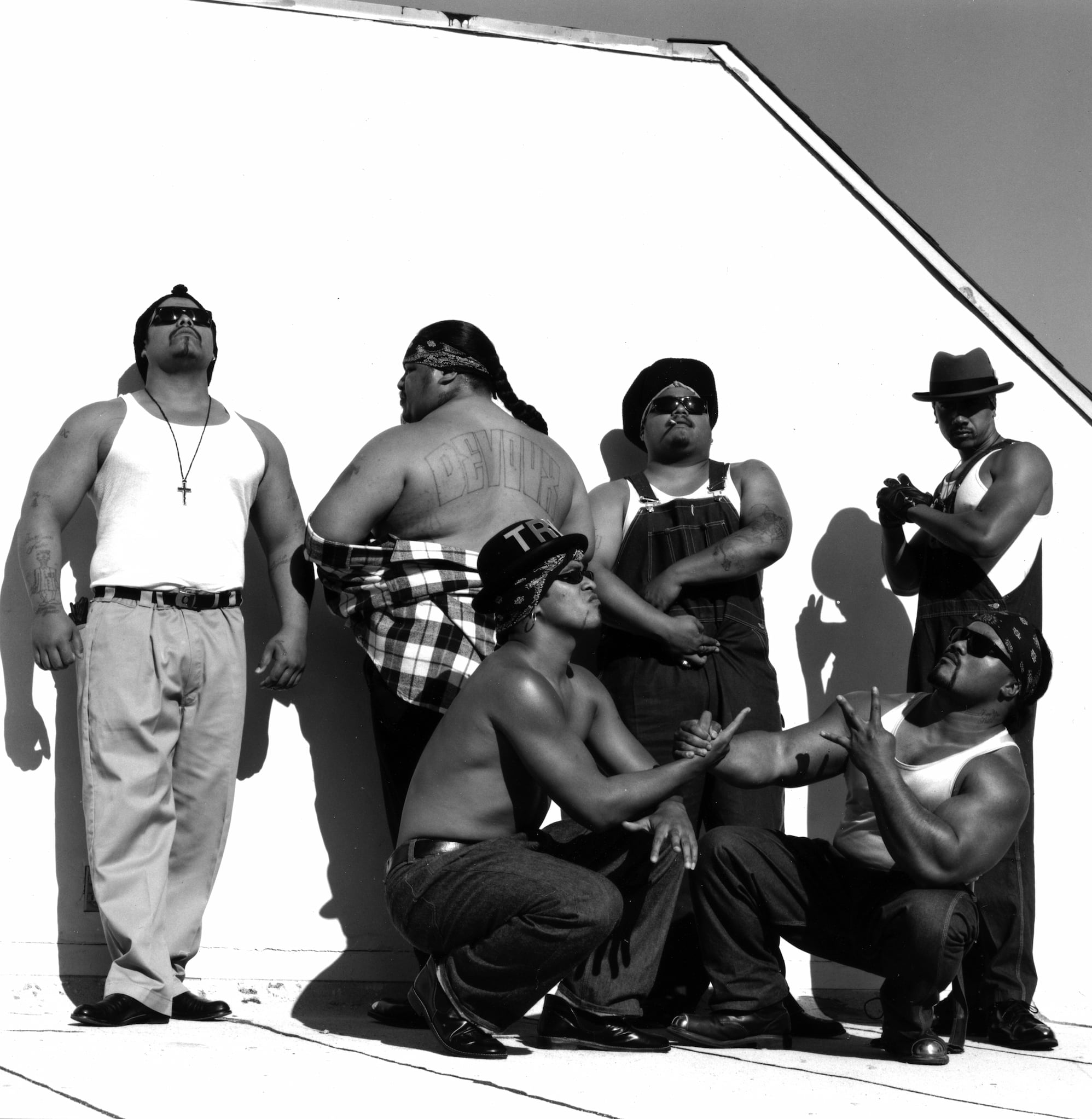 Six men of the Boo-Ya Tribe pose on a rooftop. Two members kneel in front while four members stand behind.