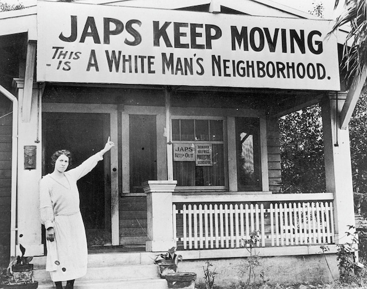 A woman stands outside of home and points to banner that reads "Japs Keep Moving / This Is A White Man's Neighborhood."