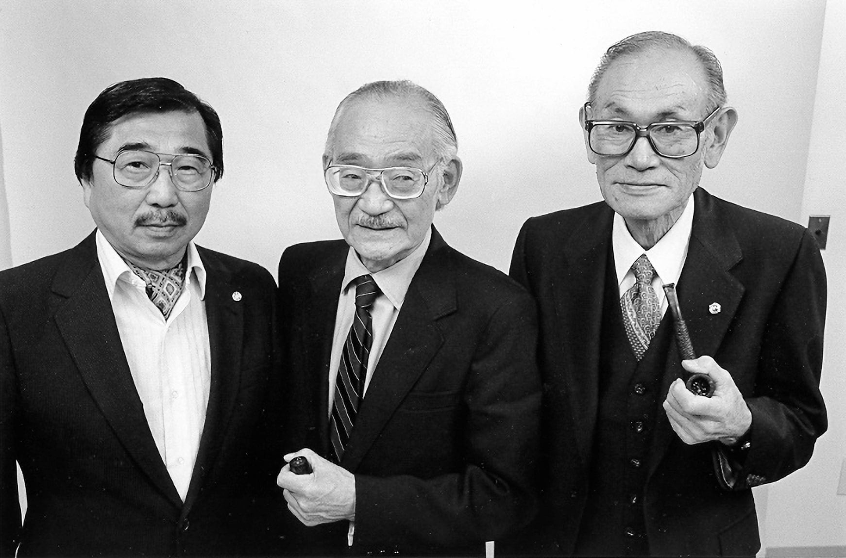 Gordon Hirabayashi, Minoru Yasui, and Fred Korematsu stand together dressed in suits.