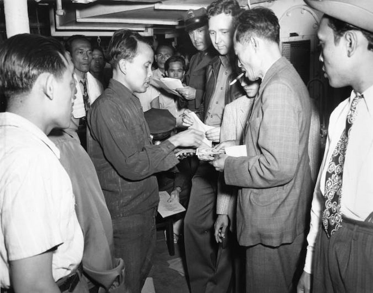 A couple of men exchange currency in a crowded room.