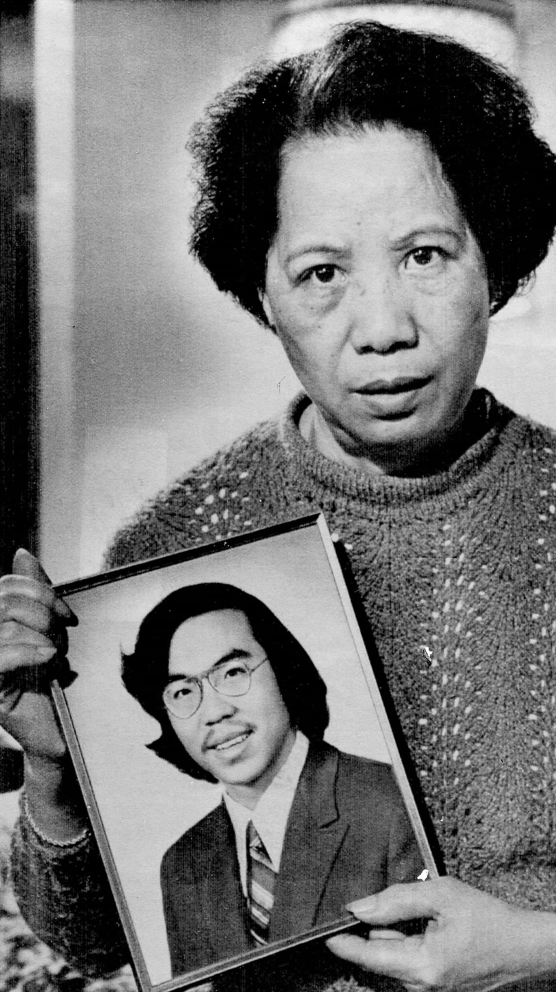 Lily Chin dressed in a knitted sweater holds up a framed portrait of her murdered son, Vincent Chin.