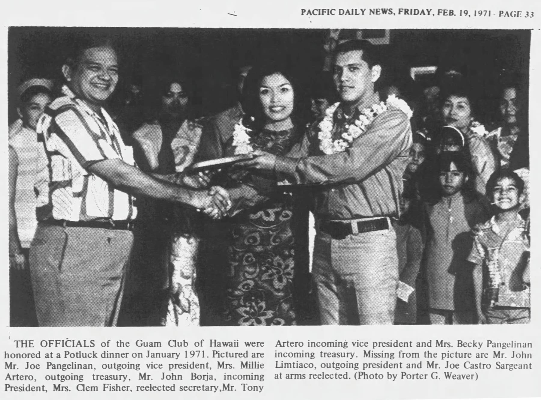 Article and photo on the Guam Club of Hawaiʻi. In the photo, a woman, at center, smiles as two men shake hands and hold a plaque.