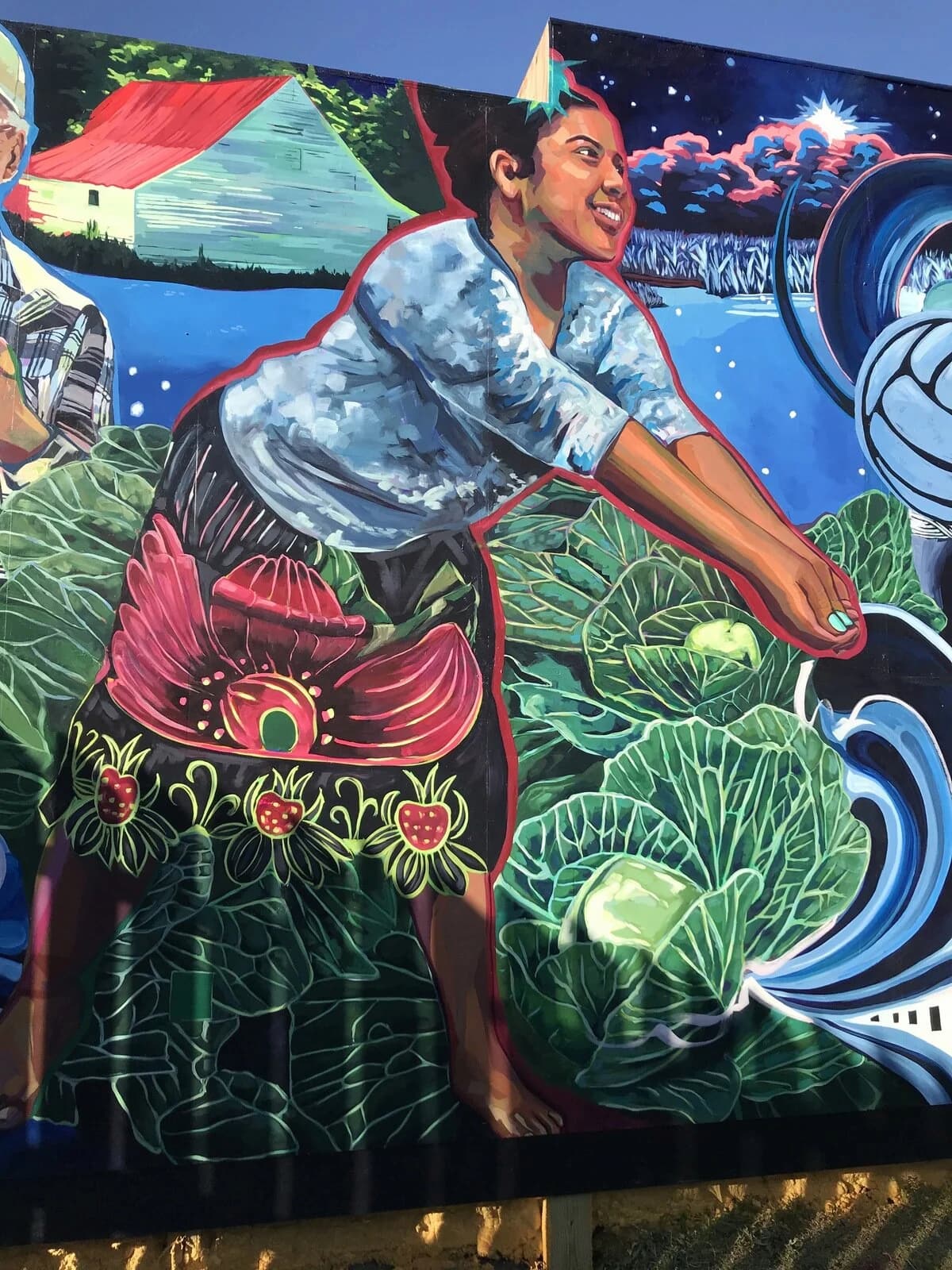 A mural dominated by blue water and green vegetation shows a Micronesian girl with her arms outstretched to return a volleyball serve.